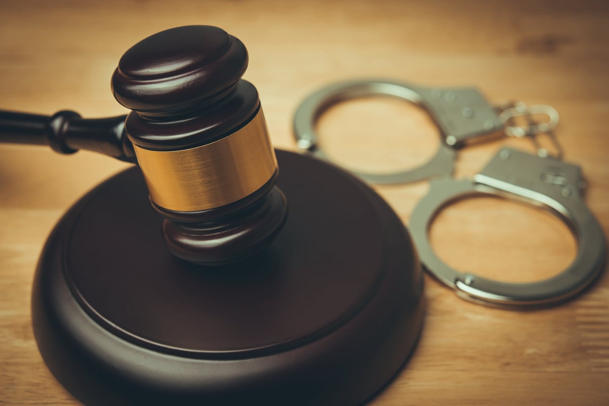 Gavel and handcuffs on a courtroom table representing solicitors for failing to surrender to court and warrant for a missed hearing