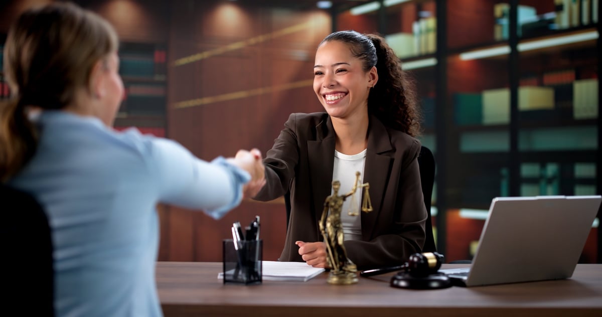 Professional UK solicitor in a modern law office meeting with a client and sealing their legal agreement with a handshake
