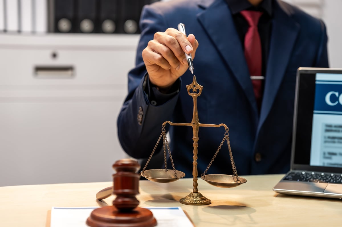 Solicitors for conspiracy to supply drugs reviewing case evidence at their desk with scales of justice